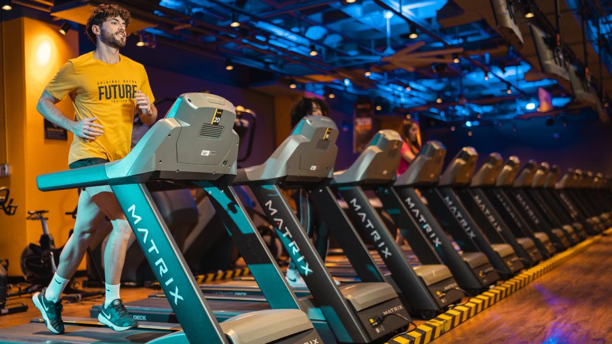 hombre de perfil corriendo en una caminadora de un gimnasio smart fit