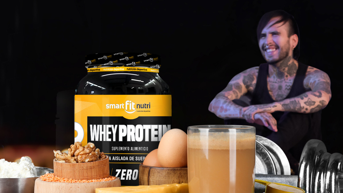 hombre sentado con en el suelo con las piernas flexionadas y los brazos recargados en las rodillas. al frente un bote de proteína en polvo, huevo, vaso con batido