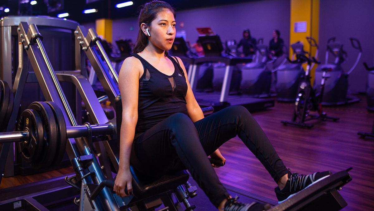 mujer realizando una sentadilla en la maquina hack en un gimnasio Smart Fit