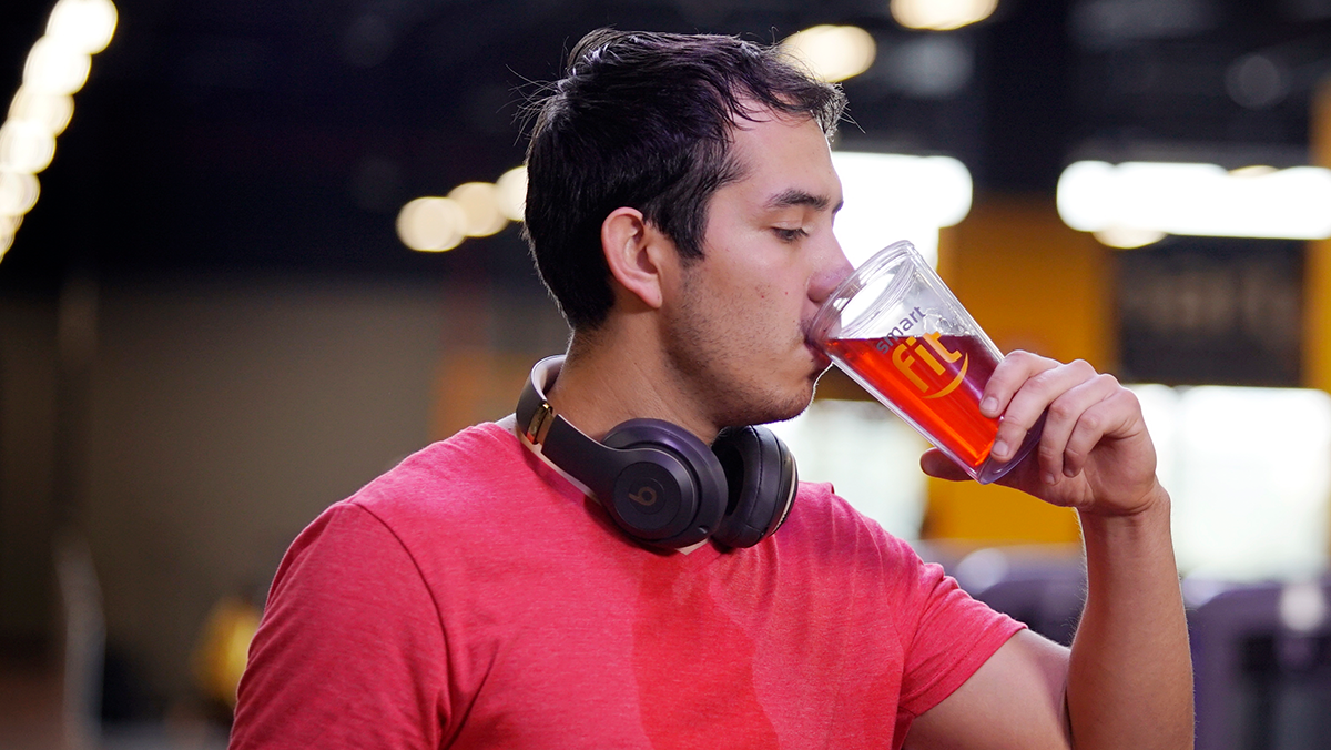 torso de un hombre de perfil bebiendo una bebia energtizante en un vaso de Smart Fit