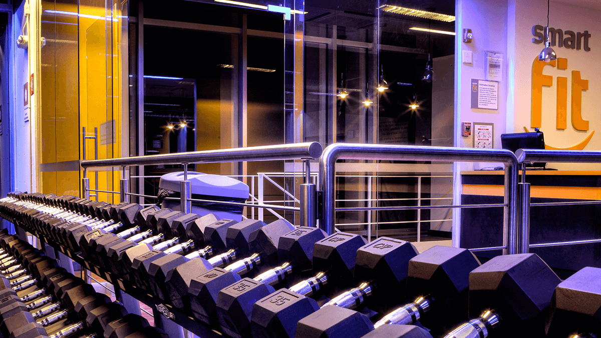 Hilera de mancuernas de distintos pesos en una área de peso libre del gimnasio Smart Fit Pabellón Cuauhtemo