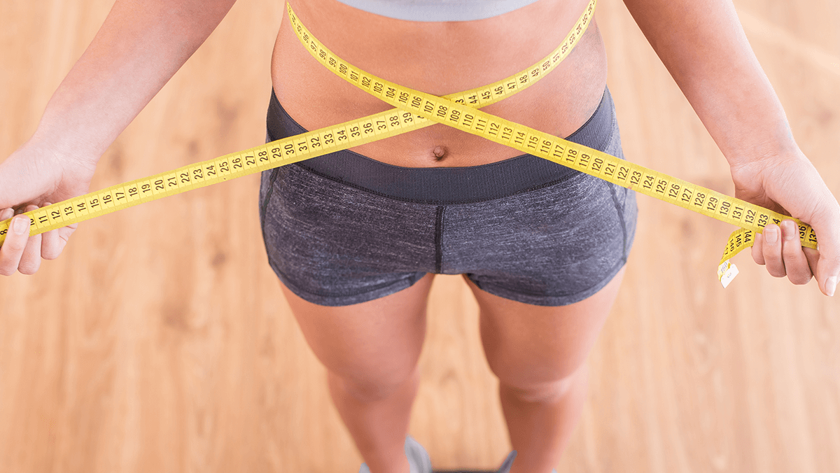parte inferior del cuerpo de una mujer con una cinta métrica rodeando su cintura