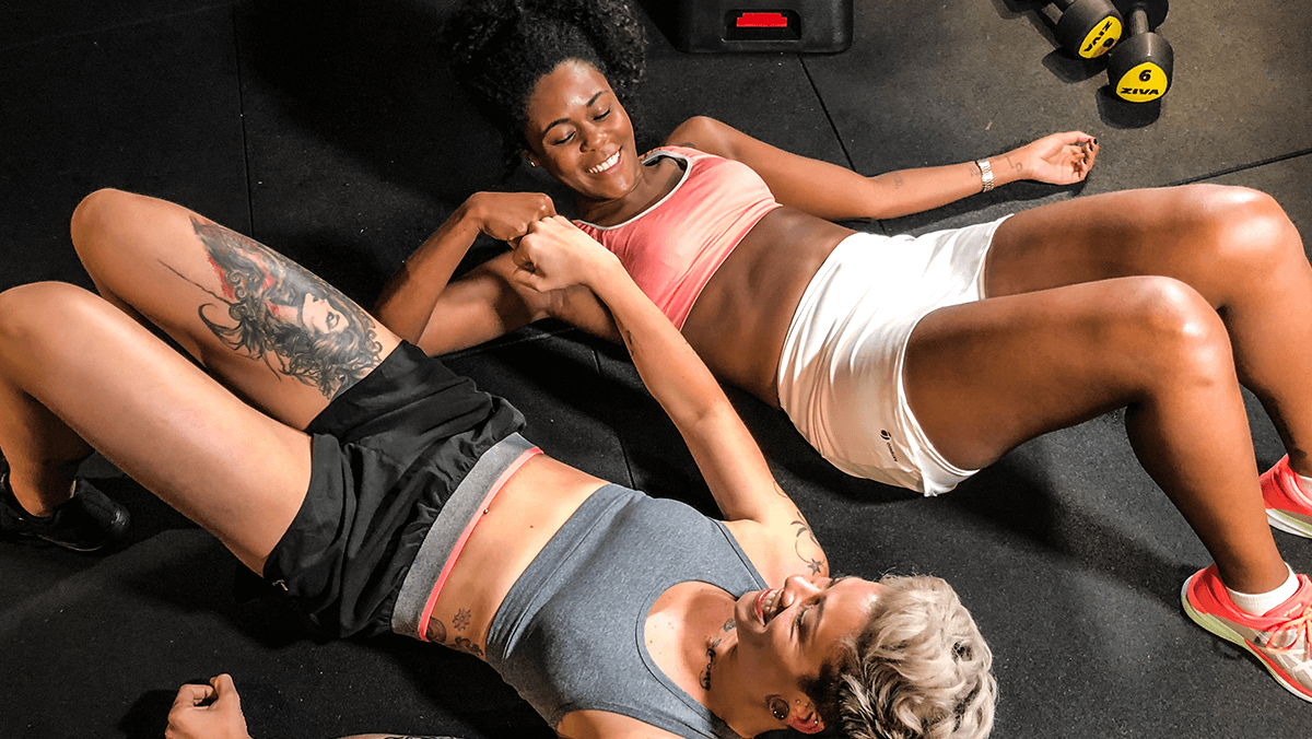 vista en contra picada de dos mujeres recostadas en el suelo chocando sus puños