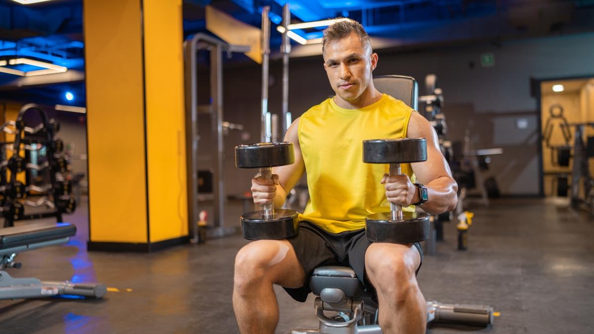 Hombre levantando pesas en un gimnasio Smart Fit, con un enfoque en entrenamiento de fuerza para desarrollar musculos y explorar que es hipertrofia