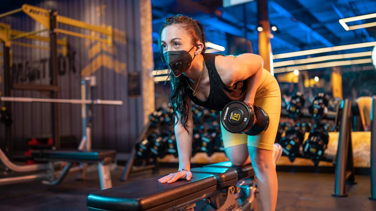 mujer realizando uno ejercicio para tricpes con mancuerna