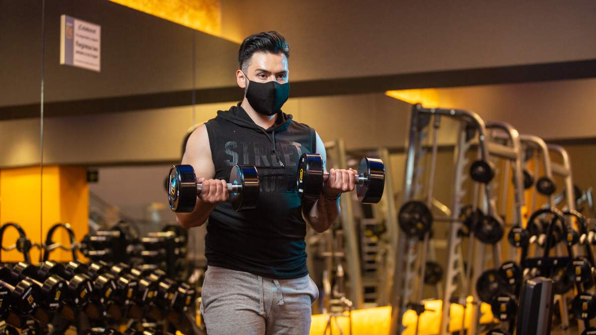 hombre realizando uno de los ejercicios básicos de brazo: curl de bíceps