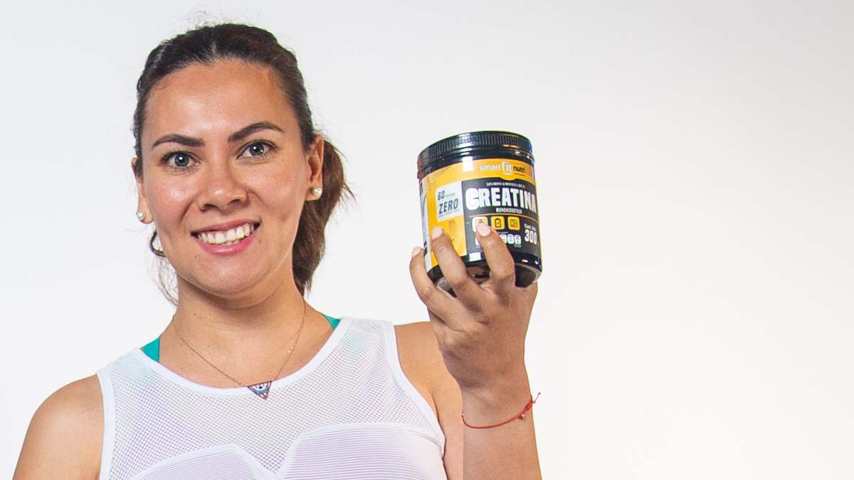 Mujer con un outfit deportivo sosteniendo un bote de creatina de Smart Fit Nutri Suplementos en la mano