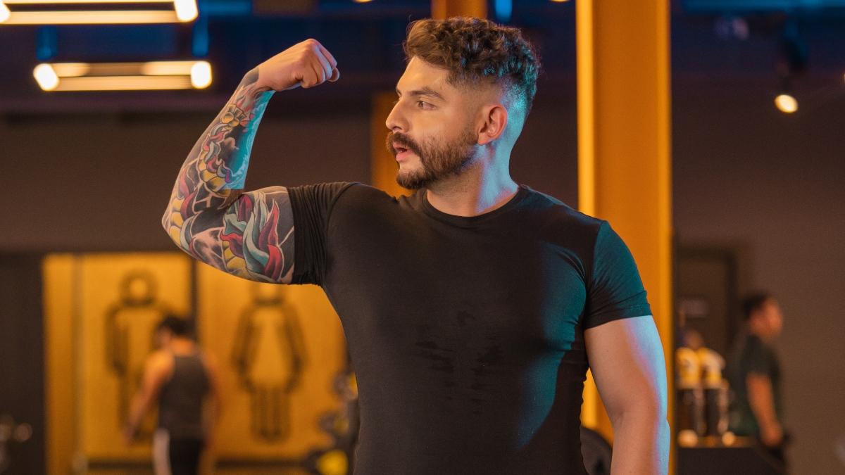 hombre en el gimnasio con el brazo levantado y flexionando, mostrando su bícep.