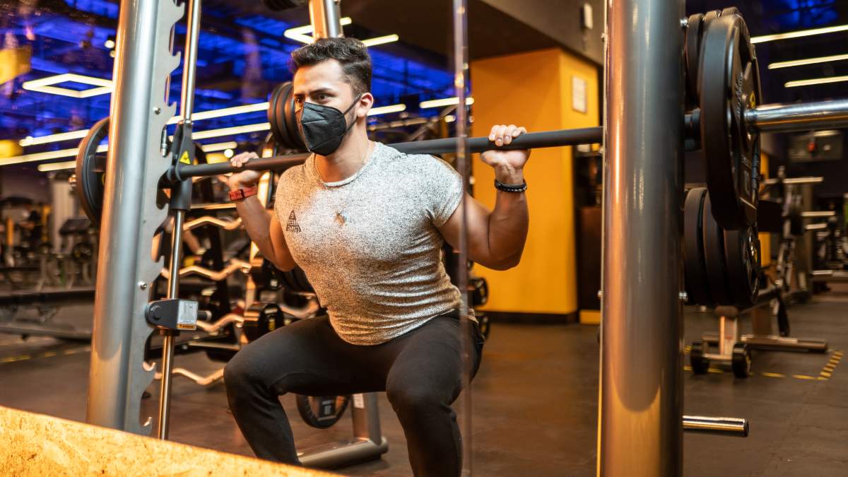 hombre realizando una sentadilla con barra en el gimnasio
