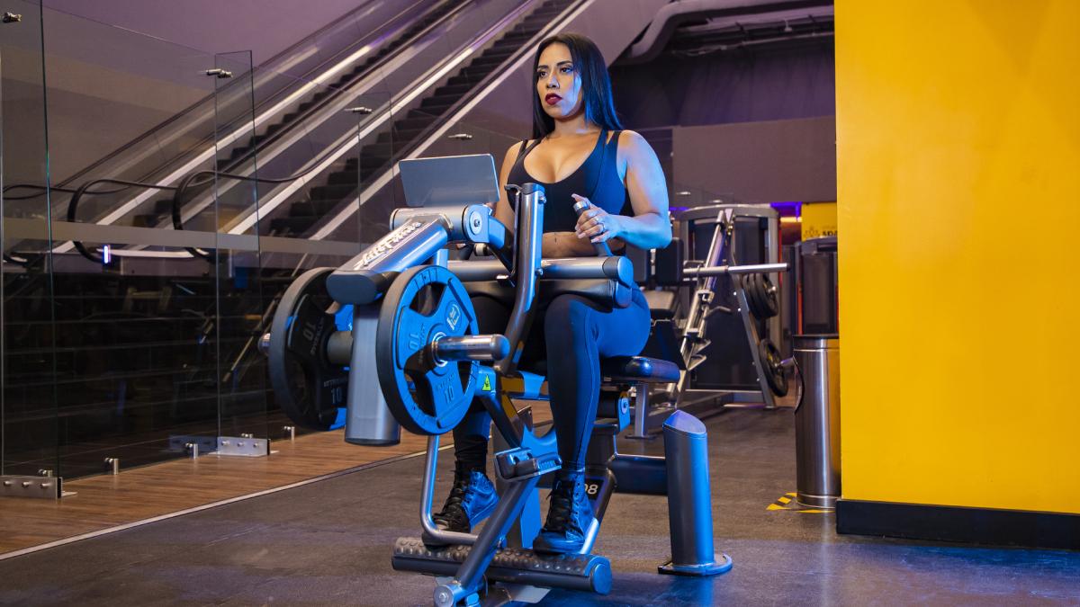 mujer sentada en una máquina del gimnasio realizando un ejercicio de tren inferior