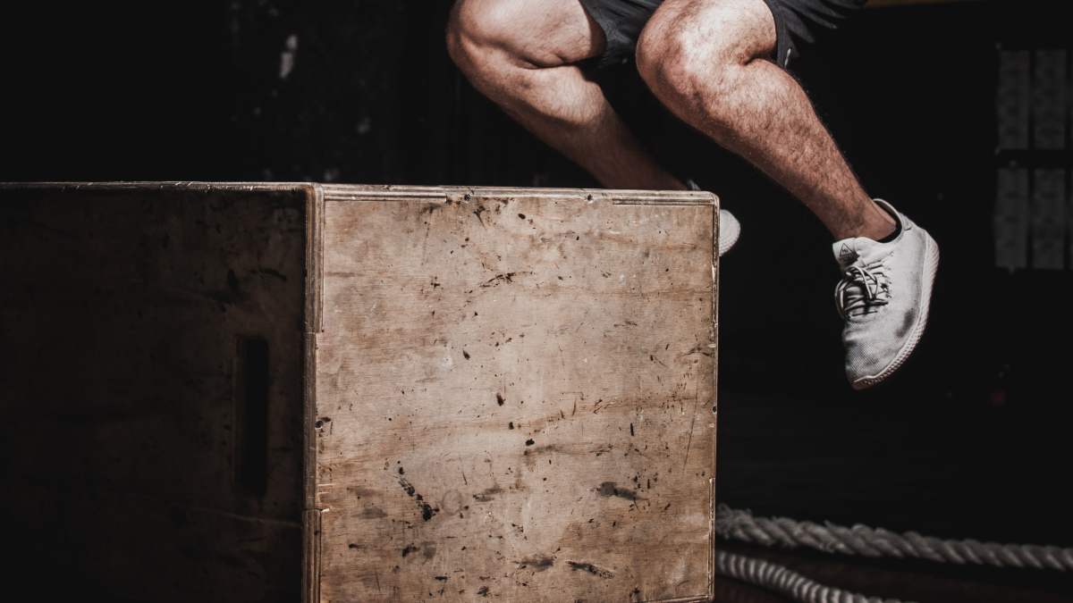piernas de un hombre realizando un salto en el banco pliométrico