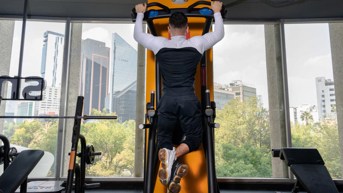 hombre colgado en un aparato del gimnasio realizando una dominada para aumentar su resistencia