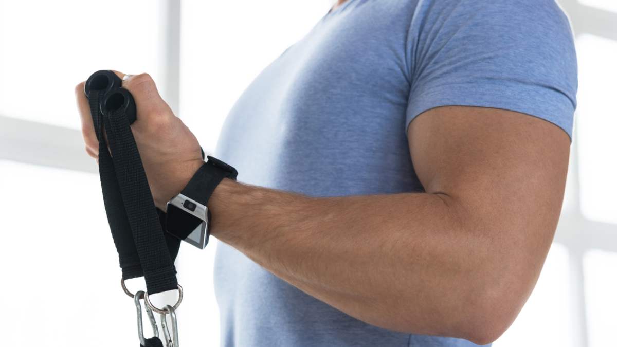 brazo de hombre realizando un curl de bíceps con ligas de resistencia
