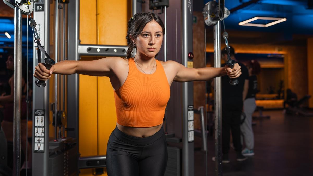 mujer joven en el gimnasio Smart Fit realizando ejercicios de poleas con determinacion, ejemplificando la motivacion para ir al gym. Ambiente moderno y equipado para entrenamiento de fuerza