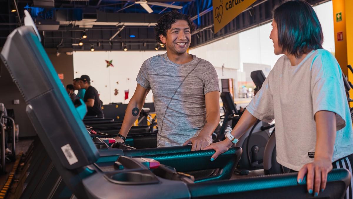 un hombre y una mujer parados sobre una caminadora del gimnasio smart fit