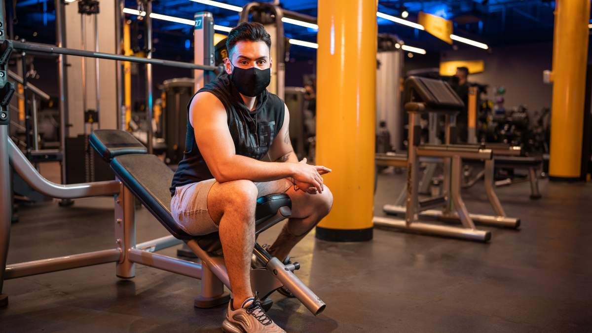 hombre sentado en un aparato del gimnasio smart fit descansando entre series