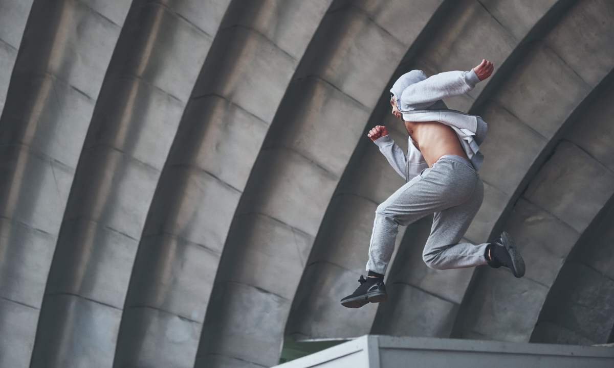 hombre realizando un salto sobre una superficie elevada. Está practicando el parkour