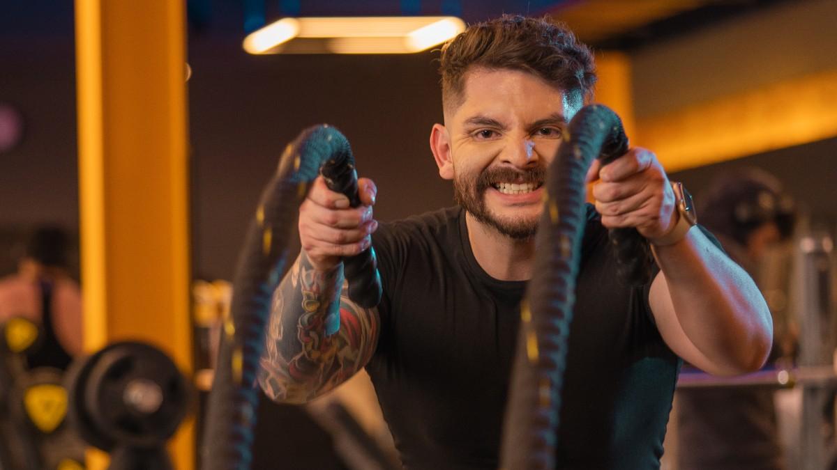 torso de un hombre con rostro de esfuerzo sosteniendo una cuerda con cada mano