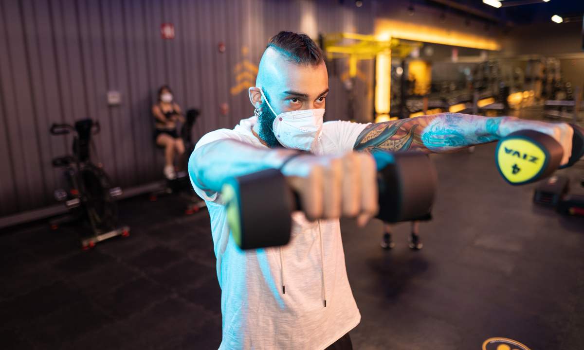hombre con mancuernas en la mano realizando ejericio en el gimnasio smart fit