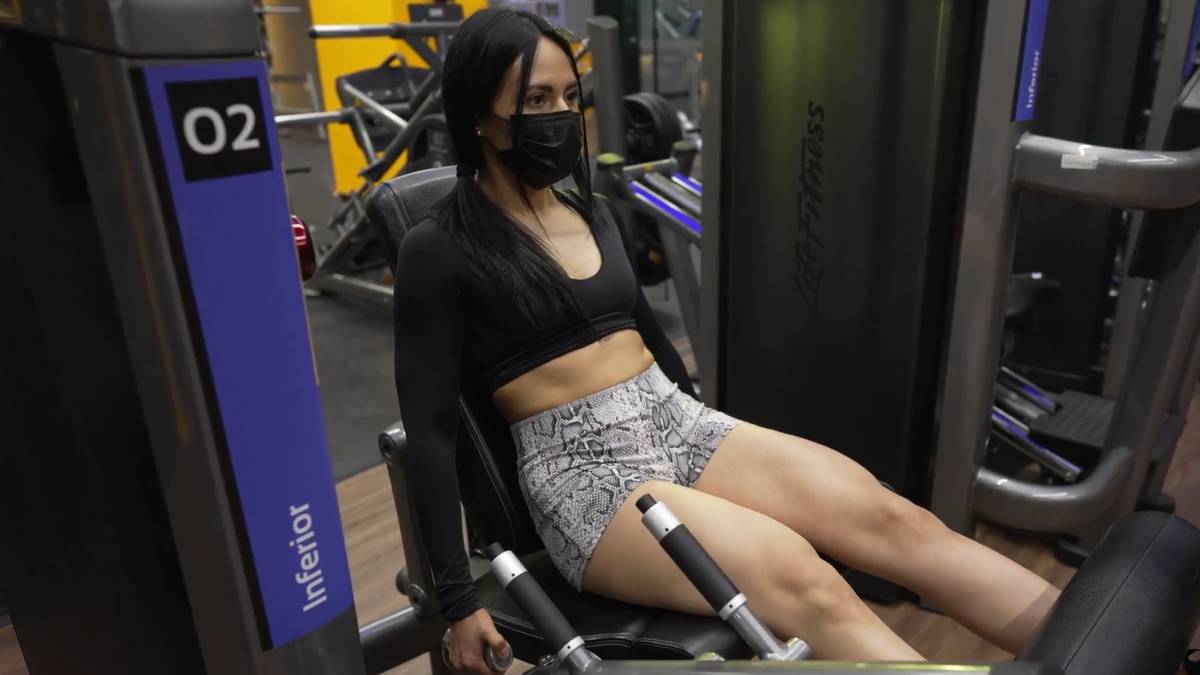 mujer sentada en un aparato de leg extension ejercitando sus cuádriceps