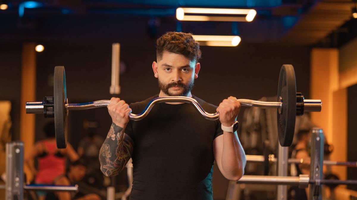 hombre realizando un curl de bíceps con agarre supino en una barra z