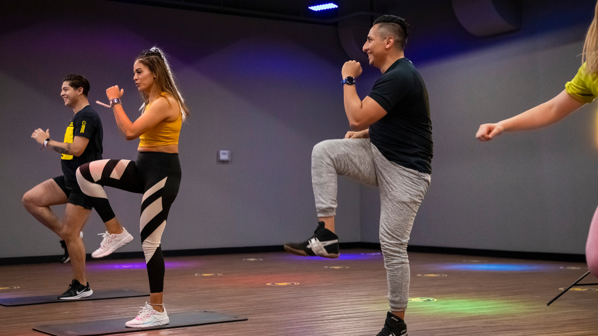 usuario y usuaria realizando ejercicio en una de las clases grupales en un gimnasio Smart Fit