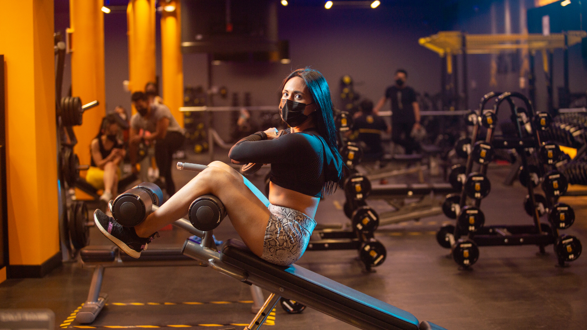 mujer ejecutando una elevación de tronco en banco inclinado, sujetando en el pecho un disco