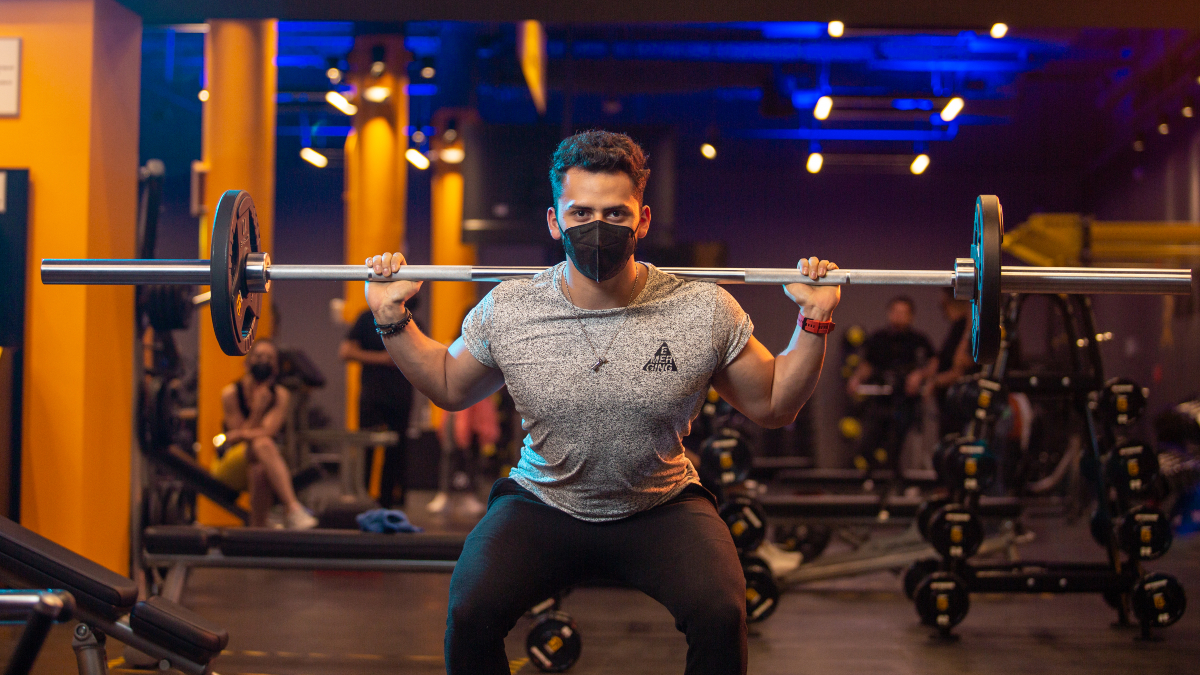 hombre joven realizando una sentadilla con una barra en los hombros