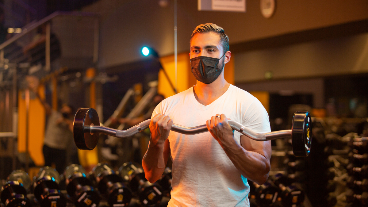 Hombre sosteniendo una barra z como parte de un curl de biceps