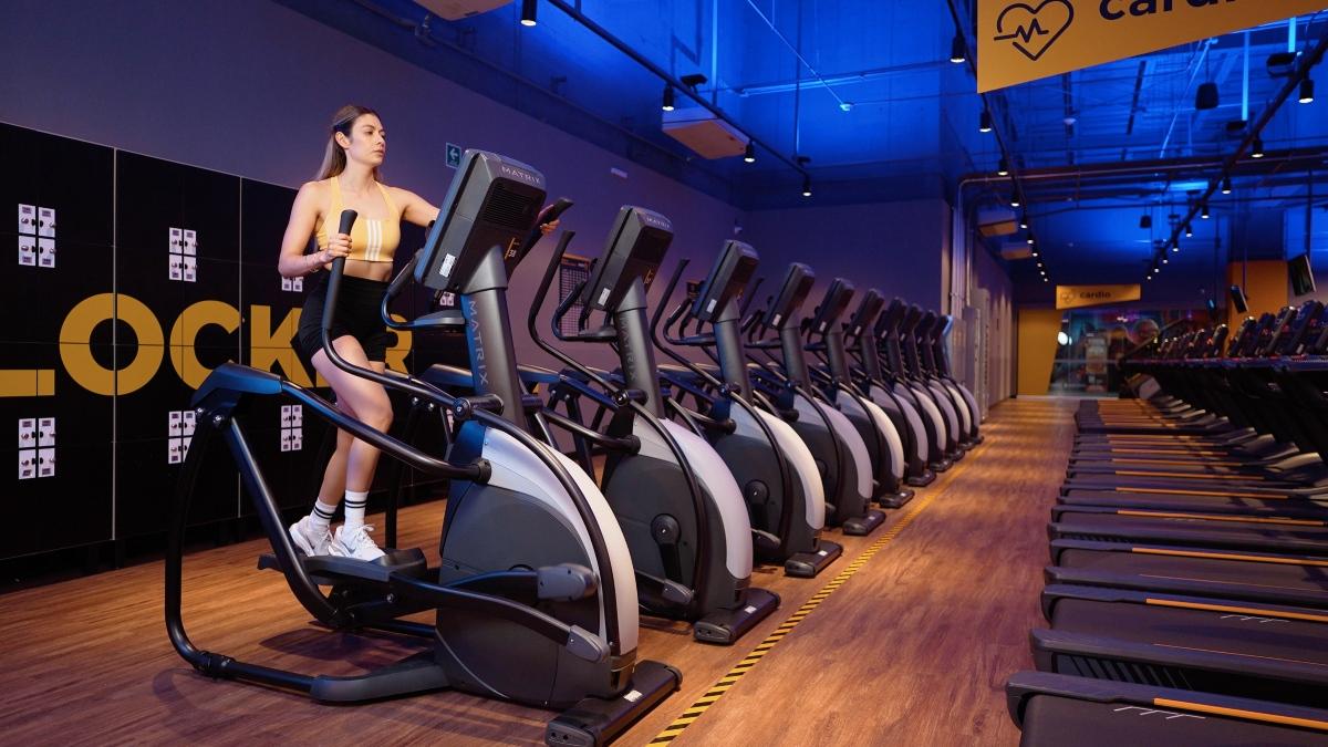Mujer realizando ejercicio en una maquina eliptica en el area de cardio de un gimnasio Smart Fit, destacando la importancia de los ejercicios cardiovasculares.