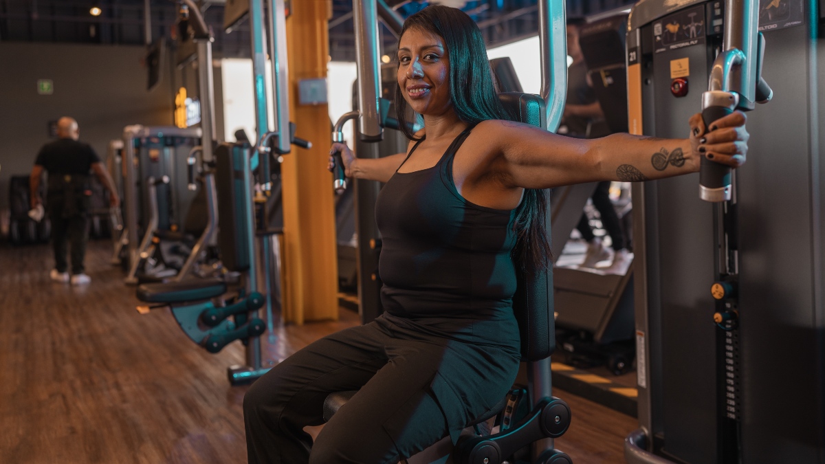 Mujer sentada sobre una máquina pec fly en un gimnasio de Smart Fit