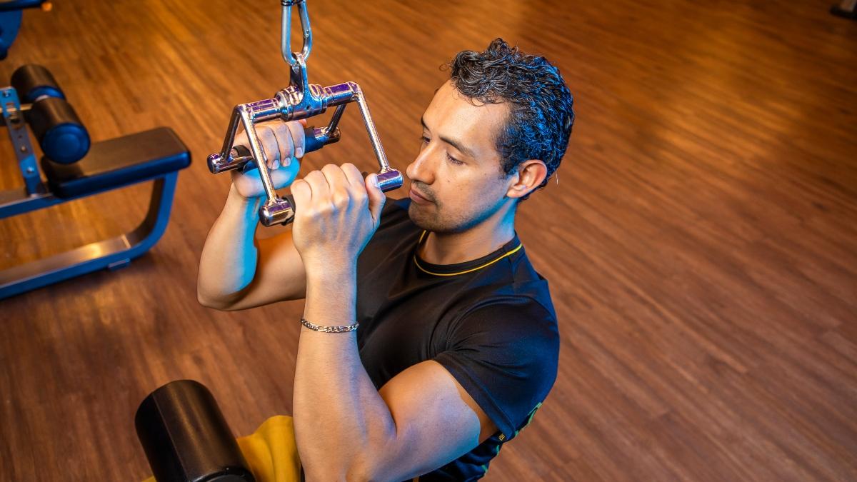 hombre sosteniendo las agarraderas de una polea en el gimnasio smart fit