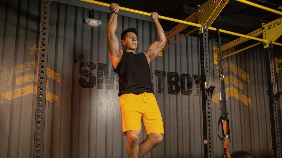 hombre colgado de una barra transversal realizando una dominada con agarre supino