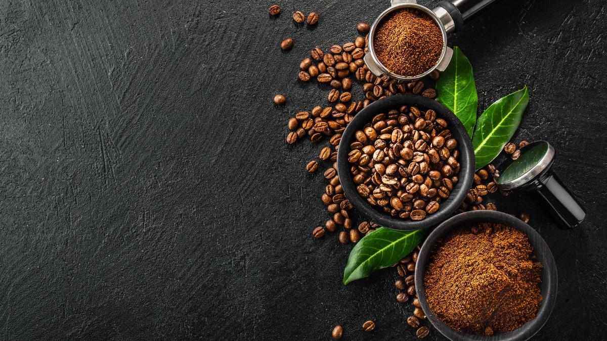 tres recipientes con café. Uno en grano y dos con café molido. Algunos granos de café alrededor de los recipientes.