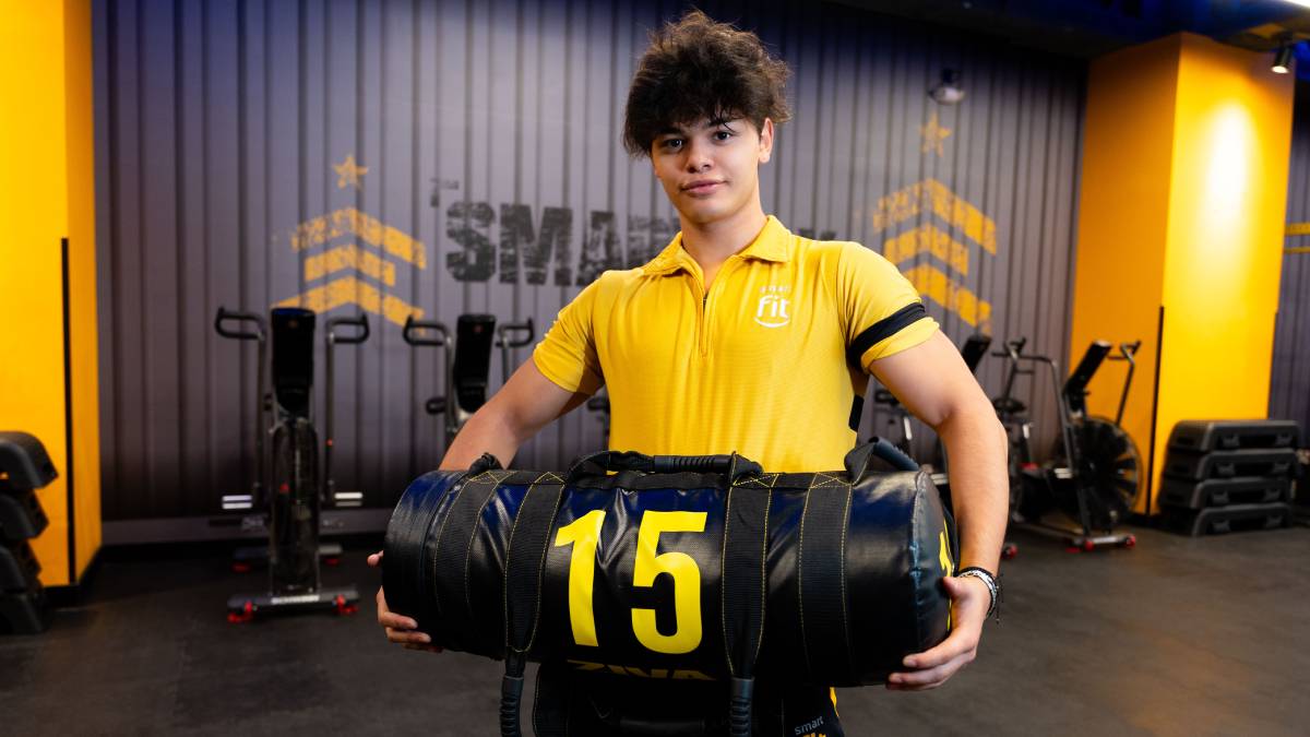 profesor de un gimnasio smart fit sosteniendo un sandbag con las dos manos