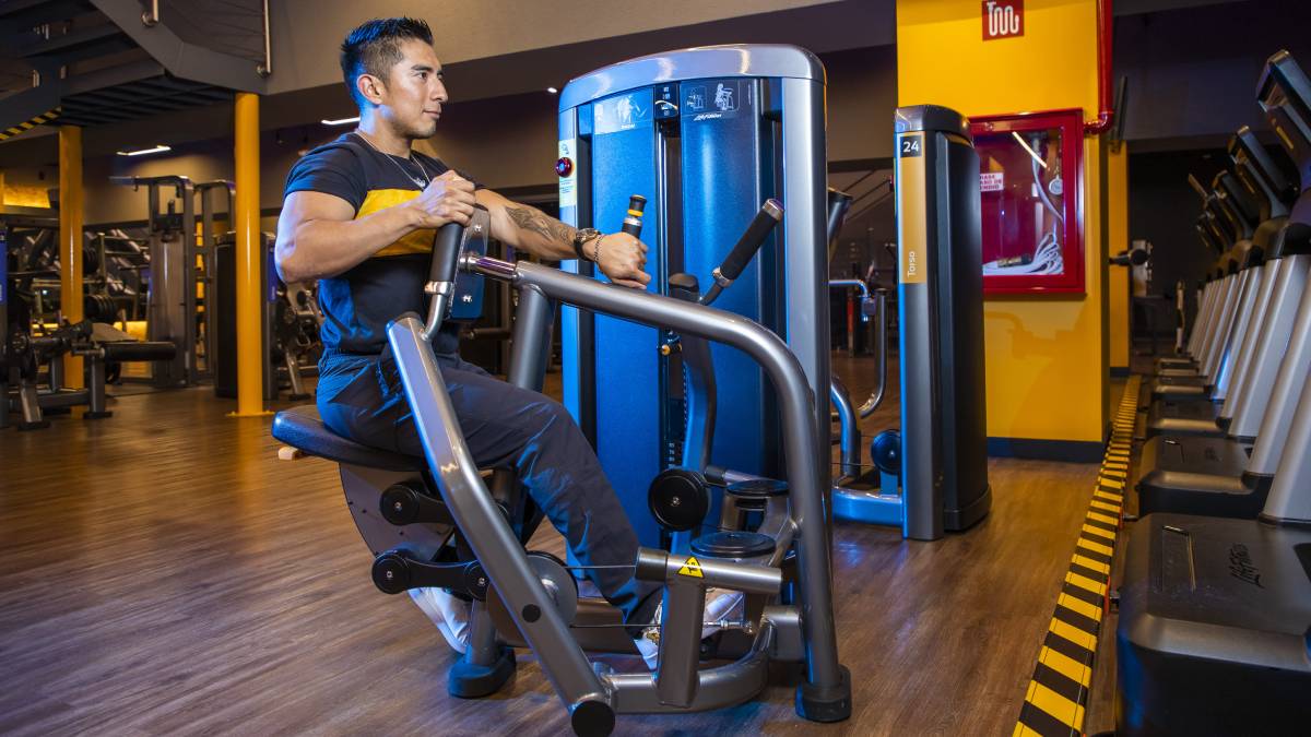 hombre sentado en una maquina de peso integrado realizando ejercicio