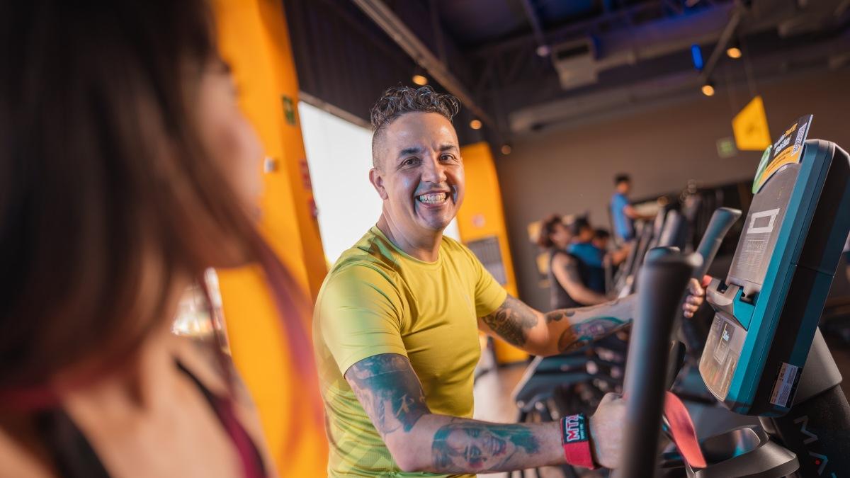 hombre sonriendo parado sobre una caminadora de un gimnasio smart fit