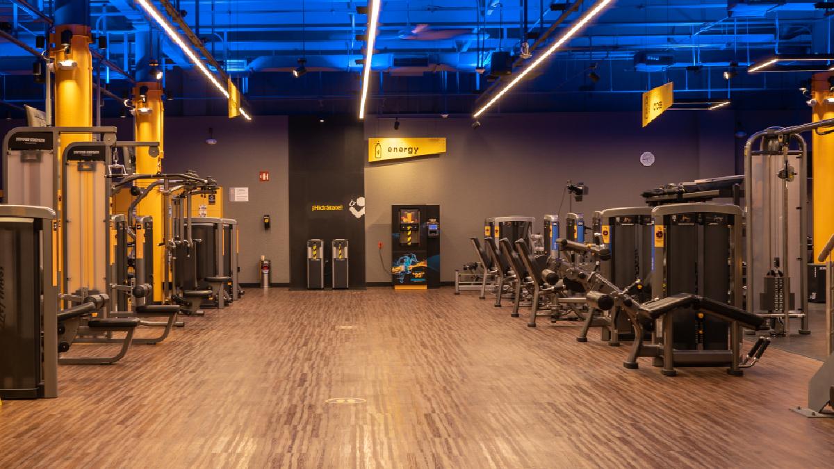 Interior de un gimnasio smart fit en playa del carmen pasillo central con aparatos de peso integrado a los costados.