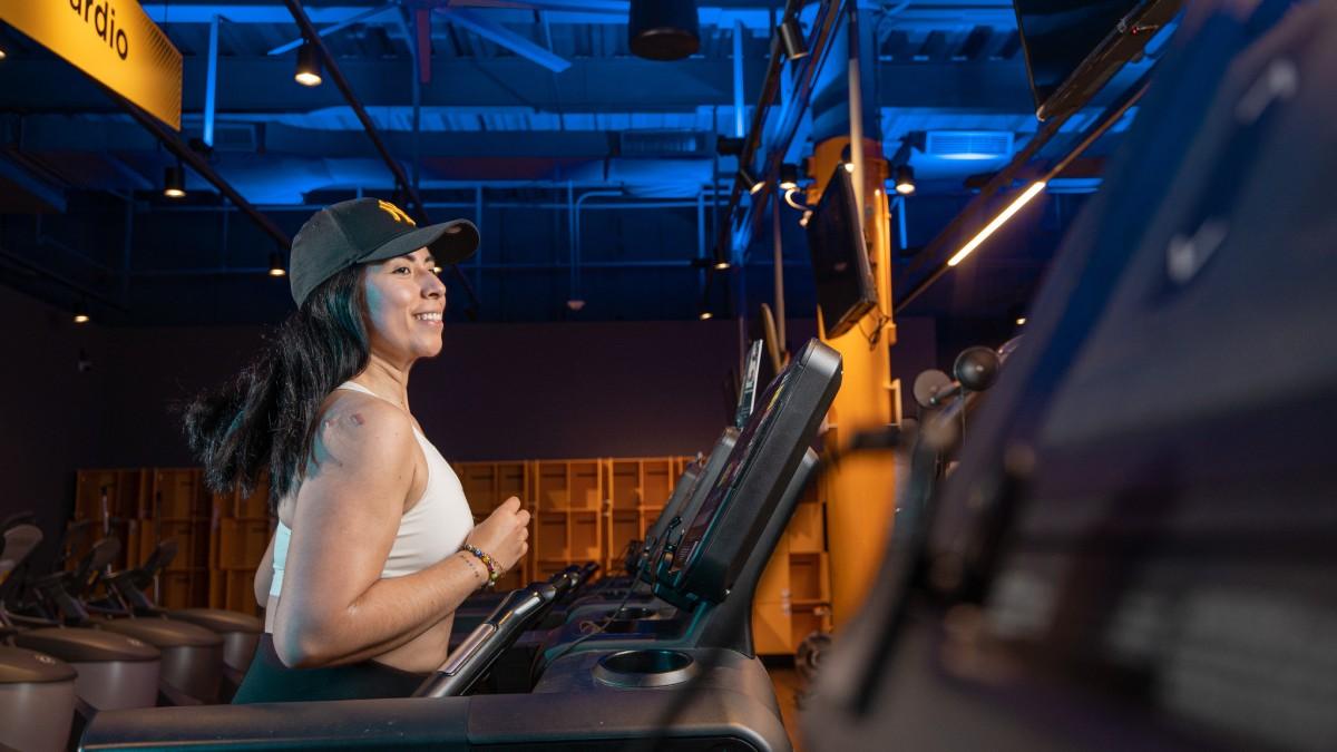 torso de mujer de perfil, corriendo en una caminadora del gimnasio smat fit