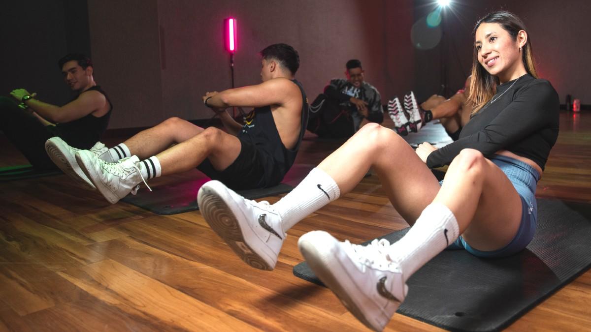 mujer sentada sobre el suelo, con las piernas levantadas y semiflexionada, torso con un leve giro hacia un costado