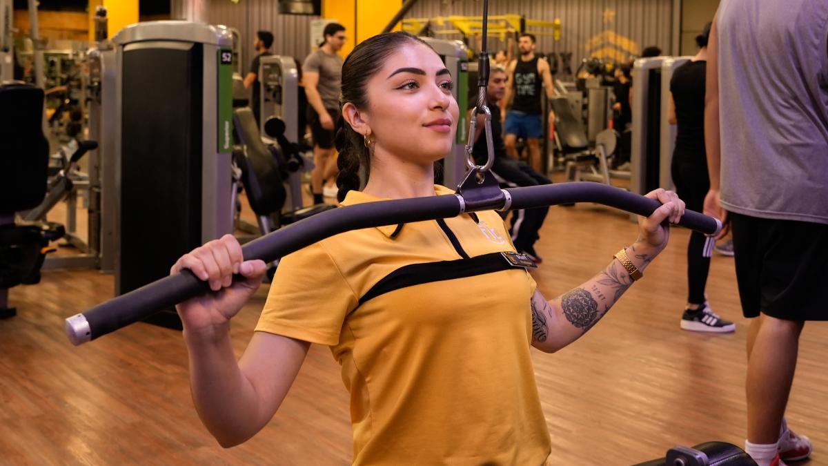 torso de una mujer sentada en una maquina lat pulldown realizando un ejercicio de jalon al pecho