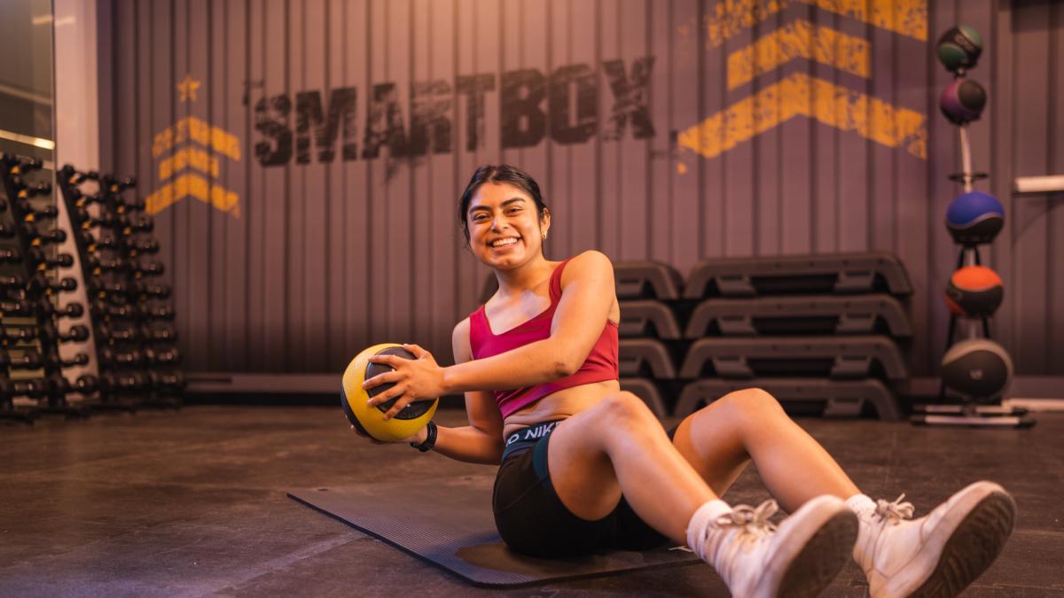 mujer sentada en el suelo de un smart box, espacio de los gimnasios smart fit dedicado a los entrenamientos funcionales.