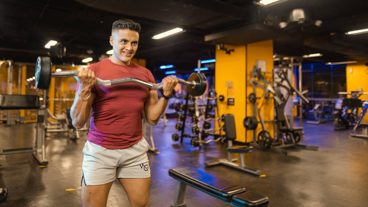 hombre realizando un curl de biceps con una barra z