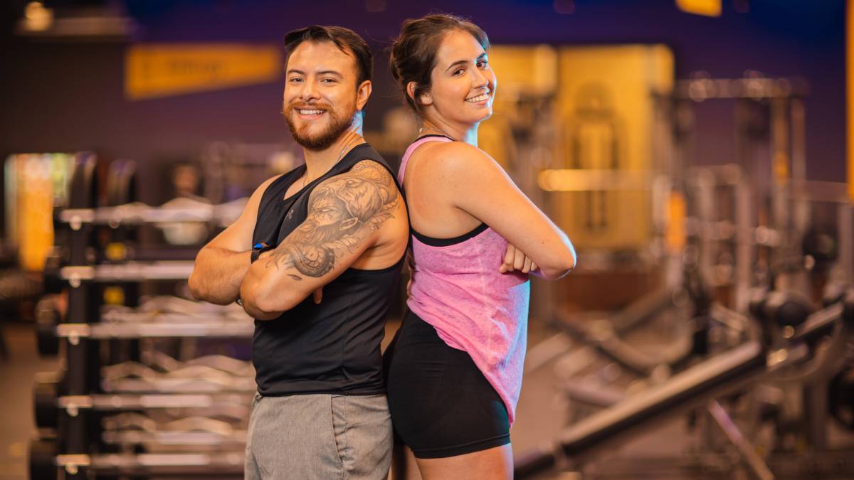 hombre y mujer de perfil, con las espaldas recargadas entre si, con los brazos cruzados y una sonrisa en el rostro