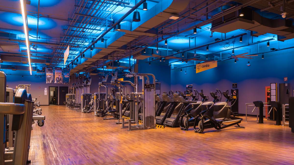 vista del interior de un gimnasio smart fit, con hileras de maquinas de peso integrado y cardio