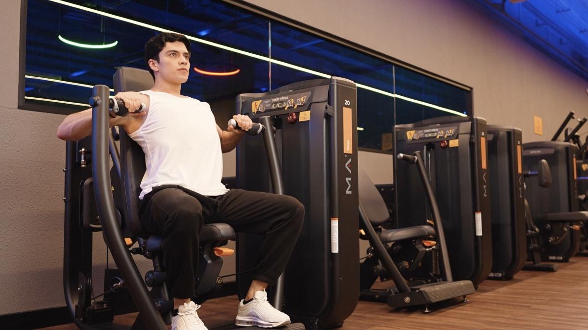 hombre sentado en una maquina de peso integrado de un gimnasio Smart Fit