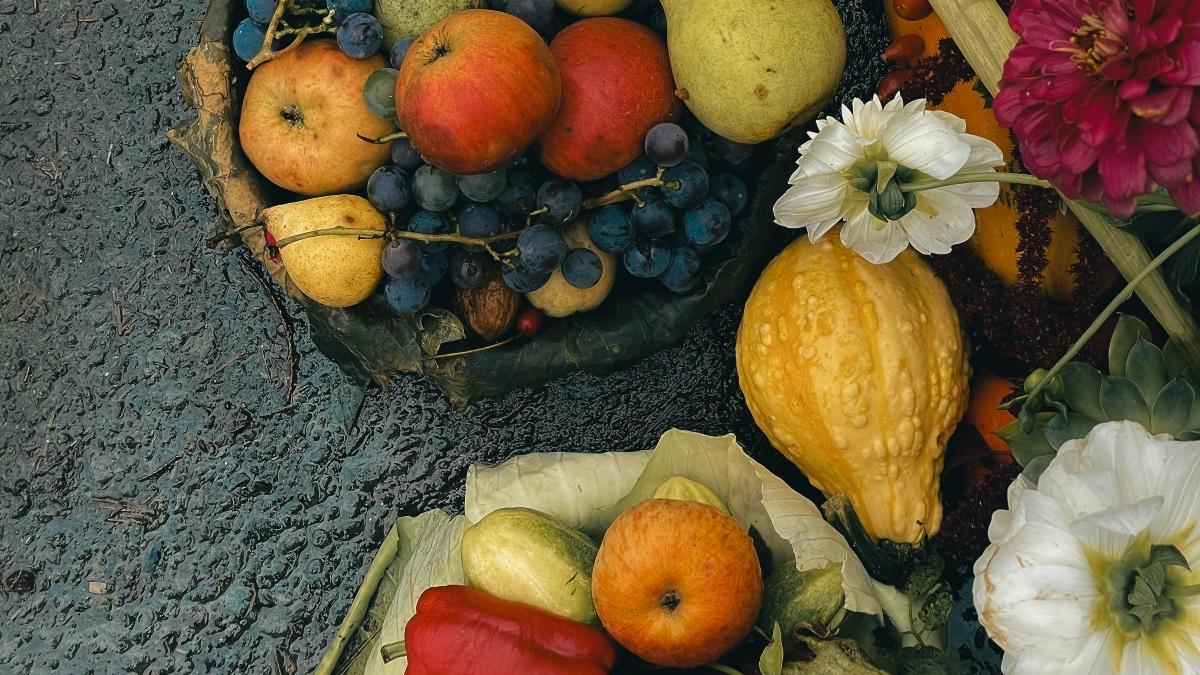 Granadas frescas en un plato oscuro, con semillas esparcidas y hojas verdes, representando uno de los alimentos de otoño mas nutritivos y versatiles.